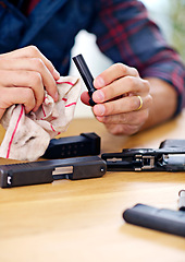 Image showing Hands, cleaning and man with firearm at table for safety, self defense and handgun assembly. Process, equipment and person with gun maintenance with cloth, magazine and wiping dust, dirt and oil