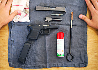 Image showing Hands, cleaning and man with gun on cloth for safety, self defense and handgun assembly. Process, equipment and person with firearm maintenance, magazine and metal parts to assemble weapon on table