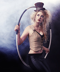 Image showing Woman, hula hoop and carnival for performer and cosplay with costume and smoke for creative and drama on dark background. Young person and thinking for dramatic, circus performance and show indoor