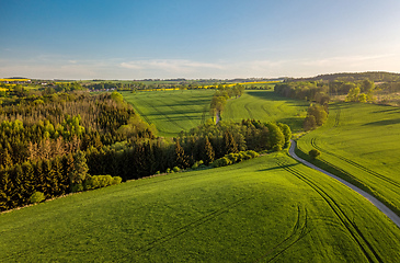 Image showing Drone flies over countryside with green field.