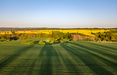 Image showing Drone flies over countryside with green field.