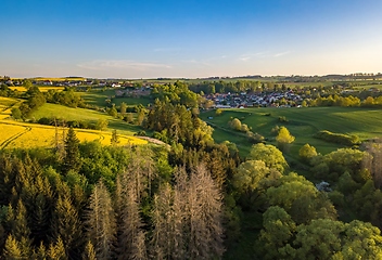 Image showing Drone flies over countryside with green field.