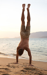 Image showing Man, beach and handstand for holiday travel on tropical island for ocean adventure, sunshine or weekend. Male person, sand and seaside fun in evening at tourism coast for break, outdoor or explore