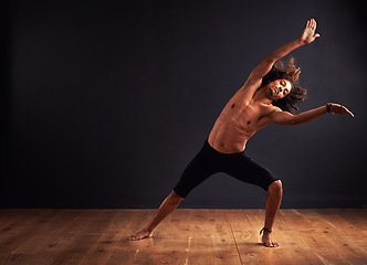 Image showing Dancer, performance and man in studio for creative, movement and rhythm on floor. African male isolated and shirtless for art deco and stretch body for theater, ballet or jazz on dark background