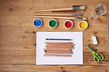 Image showing Desk, paint and brush with stationery for school project or assignment on creative art, design and drawing. Wooden table, supplies and pencil for writing exams or test with blank page for ideas.