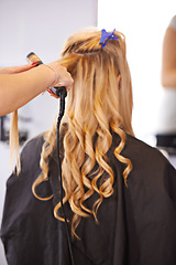 Image showing Back view, curls and hairdresser with curling iron for hair care, maintenance and styling for makeover. Balayage, waves and curly hairstyle, people and professional hairstylist at salon for beauty