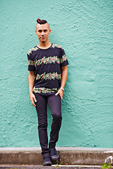 Image showing Portrait, man and trendy or outdoor by wall background and hipster fashion with funky hairstyle in city. Young guy, professional or hairstylist with happy face for unique look or modern style in town