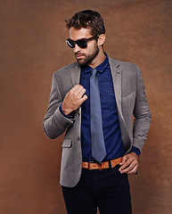 Image showing Confident, sunglass fashion and male model in studio for corporate trends on brown background for businessman aesthetic. Professional style, trendy and man with confidence in office workwear.