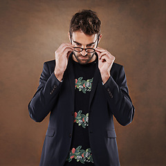 Image showing Glasses, fashion and man in studio with blazer for classy, stylish and trendy outfit with confidence. Spectacles, serious and male person with elegant and fancy style isolated by brown background.