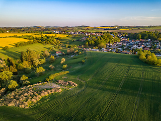 Image showing Drone flies over countryside with green field.