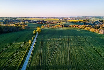 Image showing Drone flies over countryside with green field.