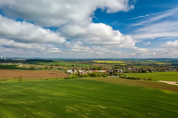 Image showing Drone flies over countryside with green field.