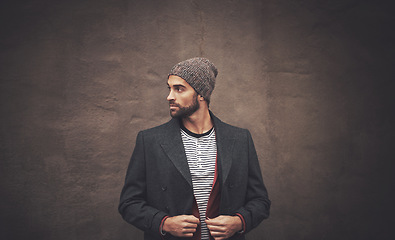 Image showing Man, serious and thinking with fashion in winter for trendy, warm clothes and cool style by brown wall. Male person, pride and pose with confidence for outfit, contemplating and thoughtful with idea