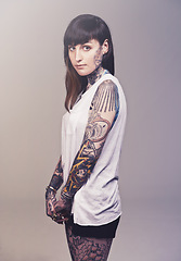 Image showing Portrait, culture and woman with tattoos, rebel and punk rock on a grey studio background. Face, person and model with creativity or artistic with heavy metal or gothic with confidence, casual or ink