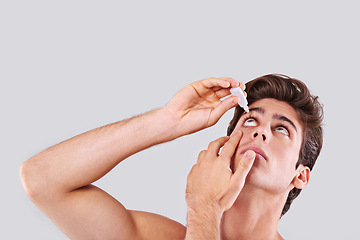 Image showing Man, allergies and treatment with eye drops for infection, sight or vision on a gray studio background. Male person or young model with pharmaceutical for optic hygiene, dry pupil or iris on mockup