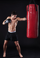 Image showing Boxer, man and punch in studio with boxing bag for workout, exercise or fight competition with dark background. Sports, gloves and serious male athlete for confidence, martial arts and fitness