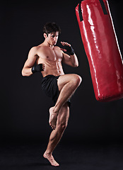 Image showing Man, athlete and boxing bag with kick in studio for self defence fighter, martial arts or black background. Male person, wellness and mockup space for strength training with gym, fitness or sport