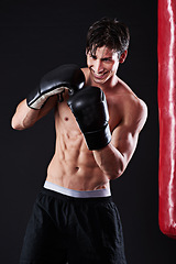 Image showing Man, boxing gloves and smile at bag for martial arts practice in studio for fitness, exercise or black background. Male person, athlete and gym fighter or training performance on mockup, sport or abs