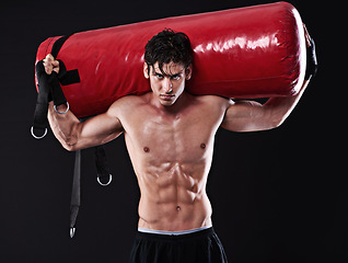 Image showing Portrait, punching bag and man with training, boxing and fitness on a dark studio background. Face, person and model with challenge and endurance with progress and wellness with health and strength