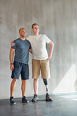 Image showing Physiotherapist, man with a disability and prosthetic leg and hug in physiotherapy, studio and gym. Male people, trainer and amputee for wellness, fitness and exercise in rehabilitation center