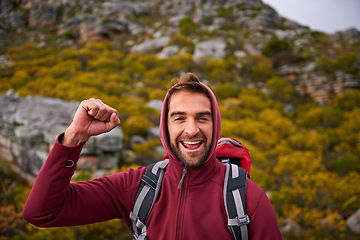 Image showing Portrait, celebration and man hiking in mountain, nature and victory with fist, wellness and health. Travel, trekking and male person with smile, happiness and adventure of guy with backpack in trip