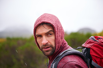 Image showing Man, mountain and hiking in rain for fitness, wellness and exercise for training and adventure in environment. Young person with backpack and rock for workout and trekking in morning with weather