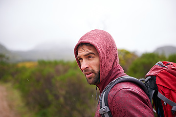 Image showing Nature, travel and man with backpack in rain, hoodie and walking on landscape, fresh air and wellness. Forest, trekking or hiking of male person for exercise, health or camping for holiday and trip