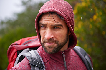 Image showing Nature, trekking and man with backpack in rain, hoodie and walking on landscape, fresh air and wellness. Forest, travel or hiking of male person for exercise, health or camping for holiday and trip