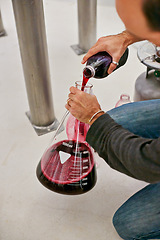 Image showing Wine, production and person in factory for winery, alcohol and drink manufacturing with beaker or measure for process. Hands of vintner or winemaker working with bottle and container for fermentation