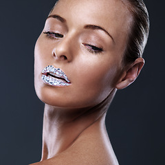 Image showing Beauty, face and woman with crystal on lips in studio with jewelry isolated on black background. Diamond, sparkle and model with creative makeup for skincare, cosmetics or art for aesthetic lipstick