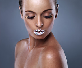 Image showing Skin, face and woman with crystal on lips in studio with jewelry isolated on gray background. Diamond, sparkle and model with creative makeup for beauty, cosmetics or art for aesthetic with lipstick