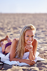 Image showing Woman, swimwear and lying in towel at beach in summer or hot weather on holiday, break and rest in Miami. Portrait, female person and smile or happy on leisure with vacation to relax and chill.