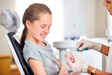 Image showing Dentures, child and dentist with toothbrush for teaching on oral hygiene, gum disease and dental care. Consultation, girl and hands of orthodontist holding teeth for cleaning, treatment and wellness