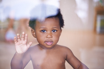 Image showing Baby, portrait and smile behind window, natural and child development for toddler growth in family home. Children, sensory education and touch with hand on glass, curious play with young African boy