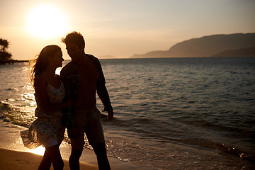 Image showing Sunset, couple walk on beach and travel for anniversary or date with bonding, love and support. Calm, ocean peace and fresh air in nature, people outdoor and wellness, trust and care in relationship