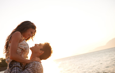 Image showing Beach, man lifting woman and ocean for travel, anniversary or date with bonding, love and support. Happy, freedom and fresh air in nature, couple outdoor and sunset, trust and hug in relationship