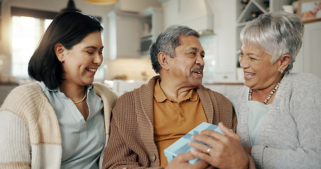 Image showing Birthday, gift and senior parents on sofa for celebration, festive event and bonding together at home. Happy family, party and elderly mother and father with daughter for present, surprise and love