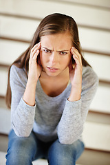 Image showing Portrait, headache and woman in house with stress, frustrated or mental health, crisis or disaster. Stairs, doubt or angry female person face with broken heart overwhelmed by anxiety, fail or mistake