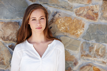 Image showing Woman, portrait and relax by stone wall in home with confidence, pride and casual outfit on weekend. Person, face and smile for holiday, vacation or peaceful getaway with shirt, good mood and calm