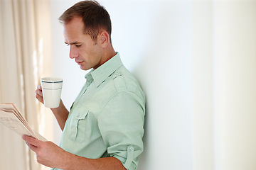 Image showing Man, newspaper and reading with morning coffee, global news articles and headlines and checking stock information. Happy, smile male person and relax with beverage to drink, lounge in apartment