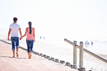 Image showing Back view, couple holding hands and walk on beach, romantic date and commitment with trust. Love, care and people together outdoor for anniversary, bonding and relax by sea with partner for travel