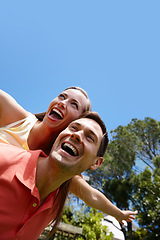 Image showing Outdoors, couple and piggyback in nature for love, marriage and bonding by flying game. Happy people, freedom and laughing on holiday for humor and commitment to fun, loyalty and connection on date