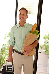 Image showing Smile, man and groceries bag in apartment with suitcase for work trip or holiday or vacation in California. Happy person, vegetables and bread as food for breakfast, lunch or dinner in house