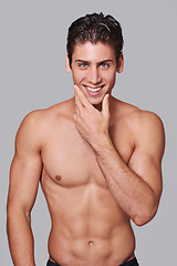 Image showing Man, skincare and smile in studio portrait with hand on face for wellness by gray background. Person, model and facial dermatology for self care, health or transformation for happy, pride or results