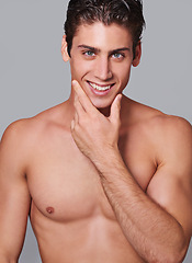 Image showing Man, skincare and happy in studio portrait with hand on face for wellness by gray background. Person, model and facial dermatology for self care, shaving or transformation for glow, pride or results