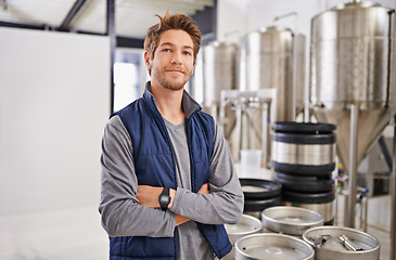 Image showing Brewery, man and portrait with arms crossed in factory with confidence, pride and container machine for manufacturing. Industrial, worker and smile in distillery with tank for brewing in warehouse