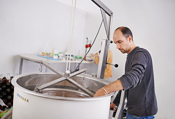 Image showing Brewery, man and container machine with manufacturing for craft beer, alcohol or production process in factory. Industrial industry, worker or working in distillery with tank for brewing in warehouse