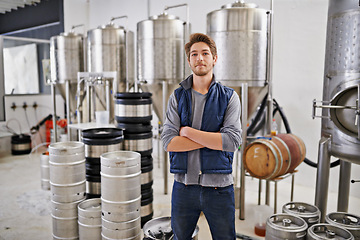 Image showing Brewery, man and portrait with arms crossed in factory with assembly line, pride and container machine for manufacturing. Industrial, worker and smile in distillery with tank for brewing in warehouse