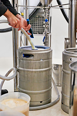 Image showing Brewery, tank and hands with pipe for craft beer in machine for production with manufacturing process, distillation or keg. Industrial industry, closeup or brewing in factory, warehouse or distillery