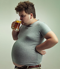 Image showing Plus size, man and drinking alcohol for unhealthy habit, belly and weight gain in studio of isolated white background. Stomach, beer and male person by beverage with swallow, calories and carbs